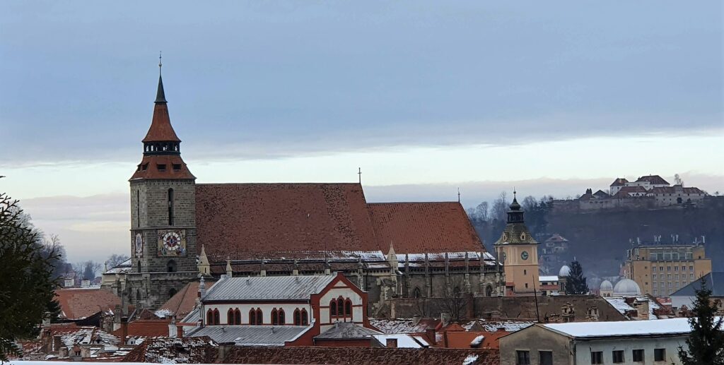 The spire and red roof in the snow.